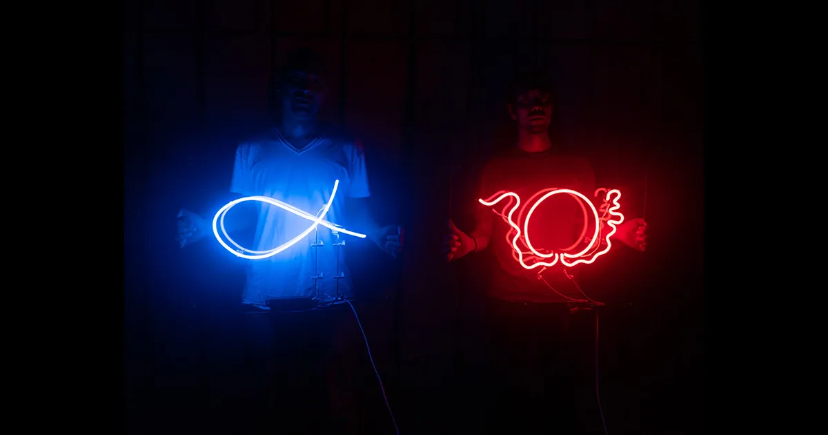 石井友人が持つ青いαネオンと福永大介が持つ赤いΩネオンのアルファオメガロゴ