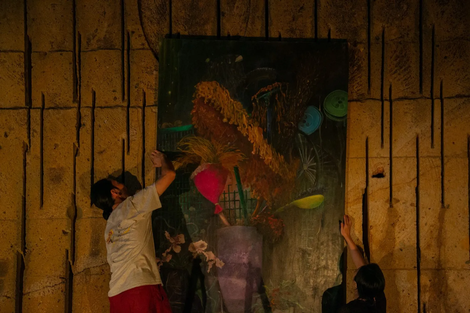 絵画を洞窟内の壁にかける福永大介と三宅砂織