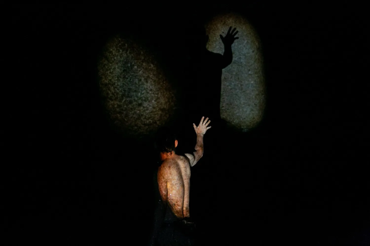 岩壁に自分の手の影を投影する石井友人