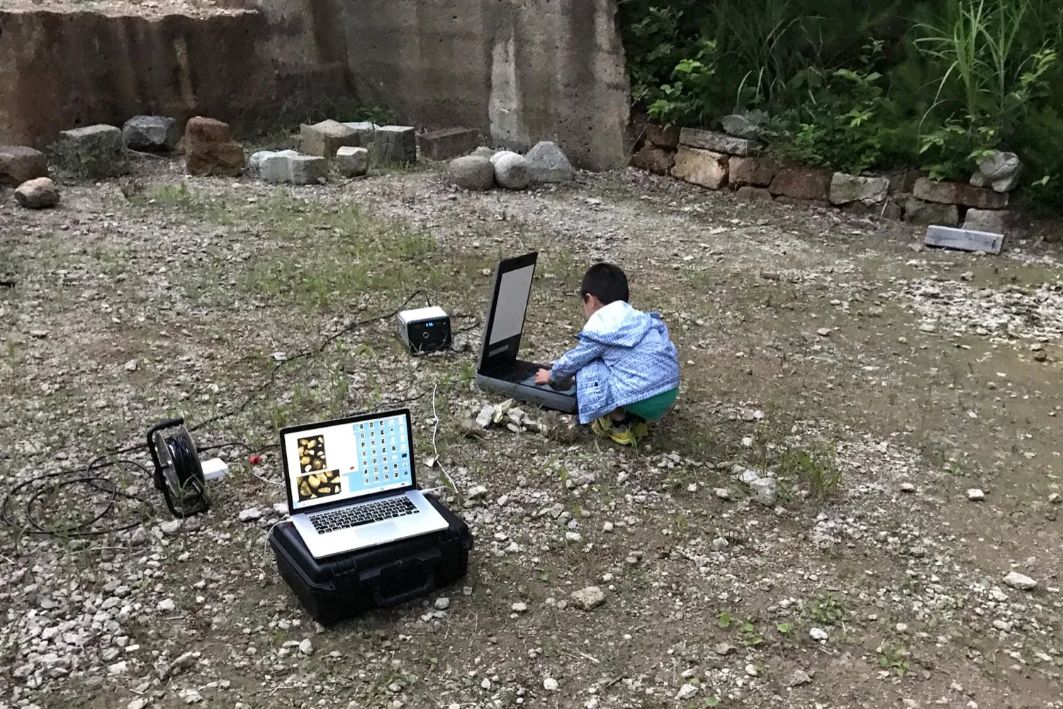 石切場跡でパソコンを使って石のデータ処理作業をする子供